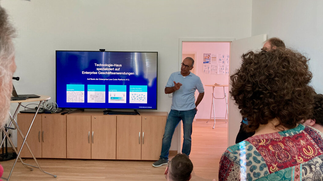 Hamarz Mehmanesh holds a presentation about mgm on a big TV in a meeting room in the QFS offices