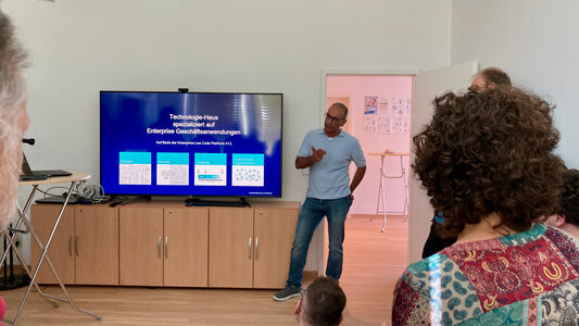 Hamarz Mehmanesh präsentiert in einem Meetingraum im QFS-Büro an einem großen Fernseher mgm