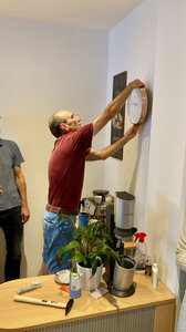 Gregor Schmid mounts a clock to the wall of the QFS office